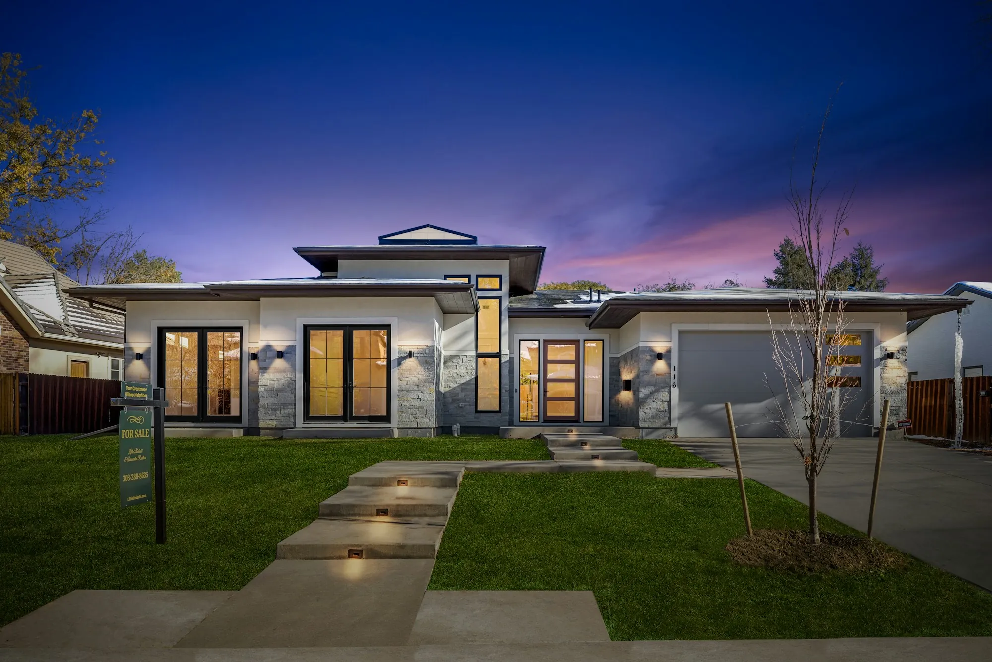 Modern single-story home with a lit front walkway at dusk