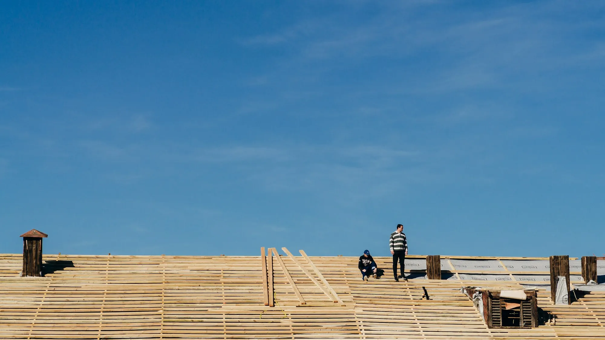 Crew laying out new roof decking on a large flat roof