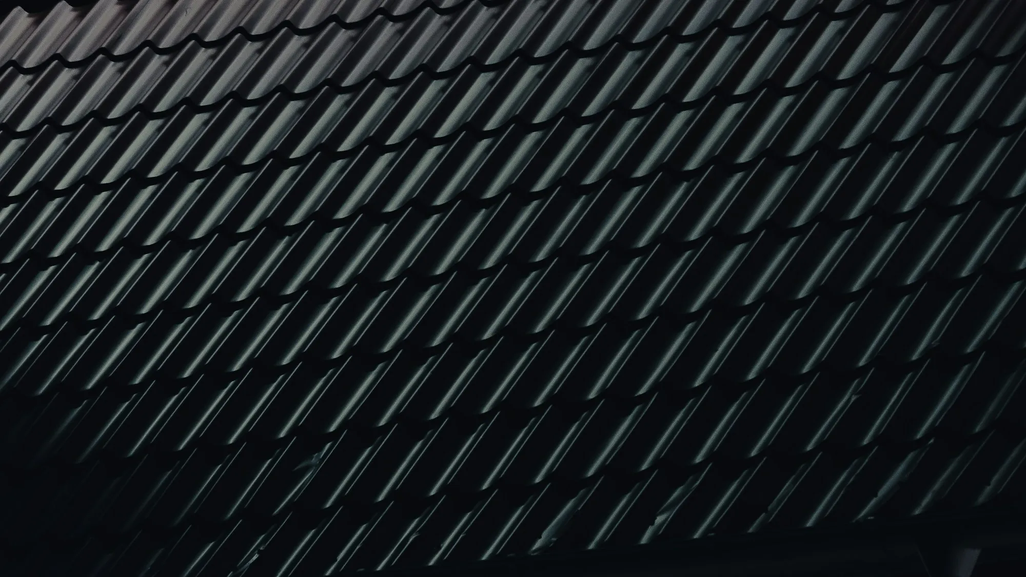 Close view of a dark, glossy roof surface laid in diagonal lines, the kind of shingle color choice East Point homeowners weigh against summer heat