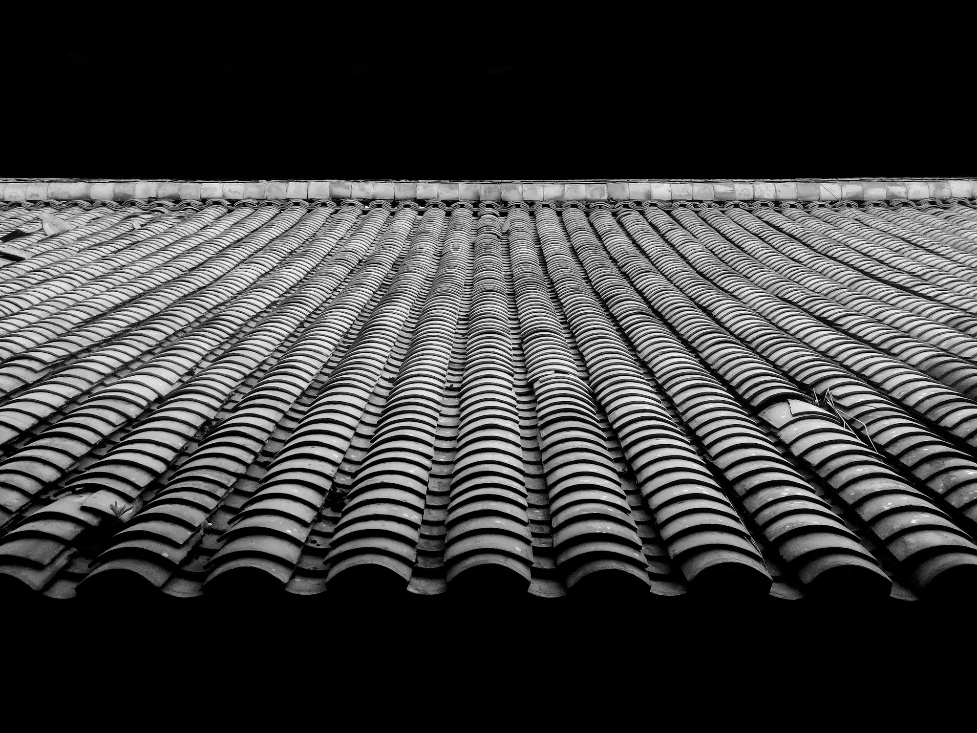 Wide view of a gray tiled roof surface stretching to the ridge