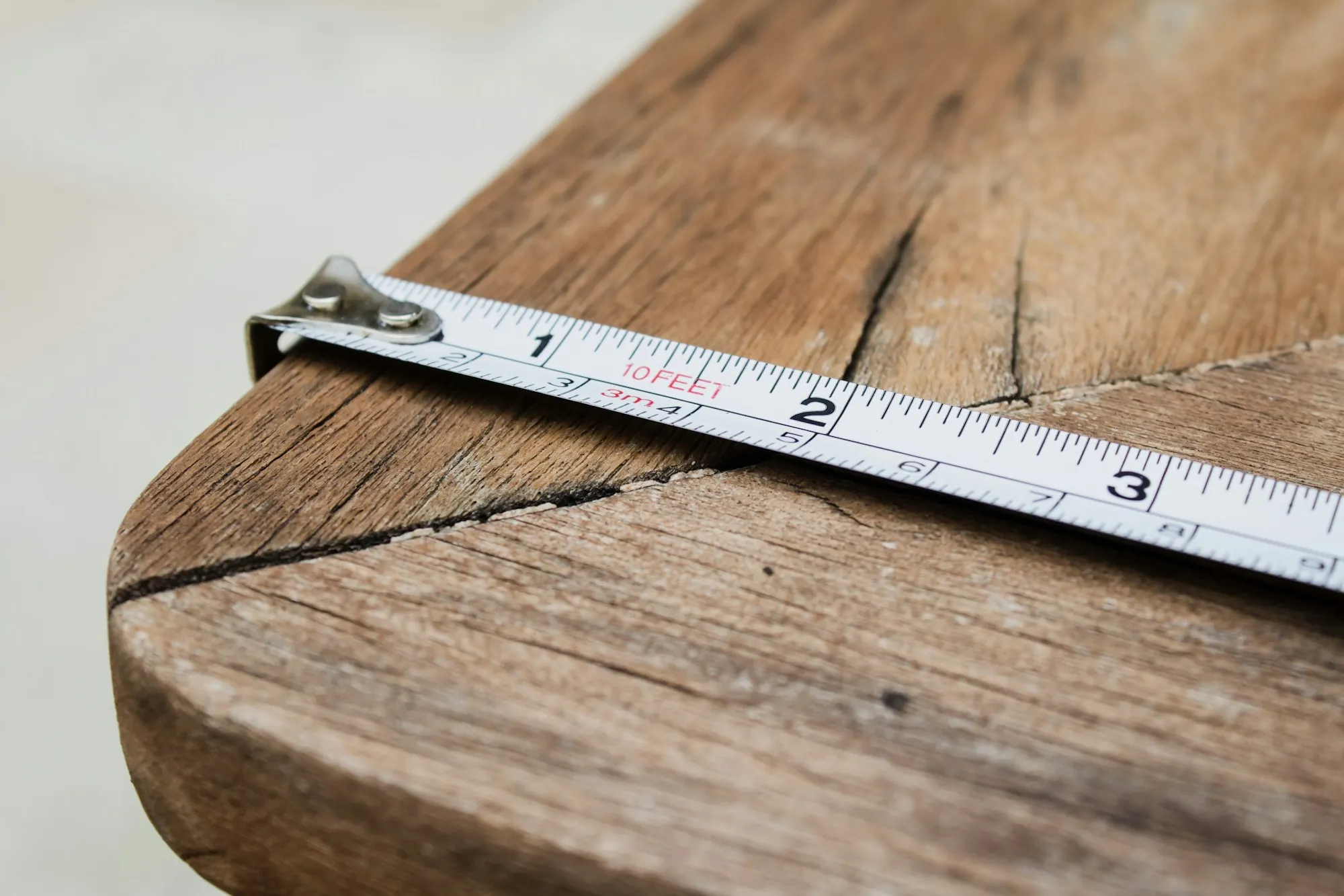 Tape measure hooked over the edge of a weathered wood plank